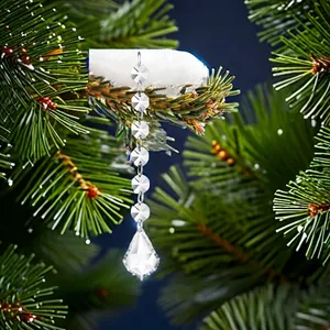 Close-up detail of a sparkling clear crystal bead chain ornament on a snowy Christmas tree branch