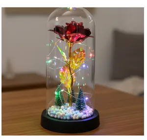Vista detallada de una rosa roja artificial en una cúpula de cristal con luces LED de colores