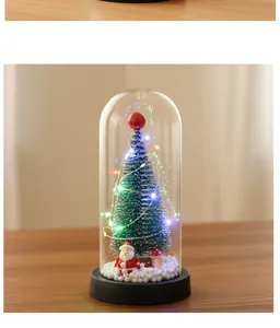 Detalle de mini árbol de Navidad brillante y figura de Papá Noel en cúpula de vidrio.