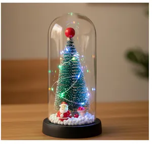 Vista de primer plano de un mini árbol de Navidad decorativo en cúpula de vidrio con luces LED