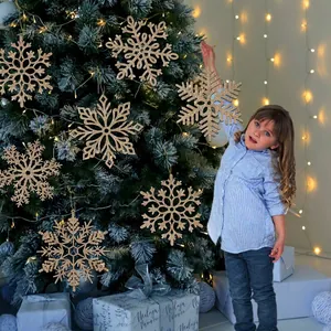 Champagne gold glitter snowflake ornaments decorating a snowy Christmas tree indoors