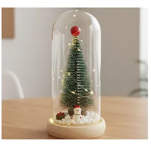 Primer plano de un mini árbol de Navidad en cúpula de vidrio con LED y muñeco de nieve