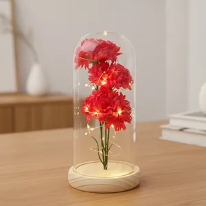 Ewige künstliche Nelken in Glaskuppel mit warmen LED-Lichtern auf einem Holzsockel