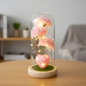 Elegante künstliche Nelken in Glaskuppel mit warmen LED-Lichtern und Holzsockel.
