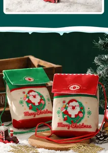 Detailaufnahme von roten und grünen Weihnachts-Geschenktüten aus Samt im Schnee