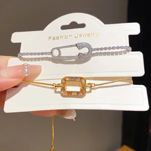 Close-up of 18K gold-plated bracelets with colorful zircons and safety pin design.