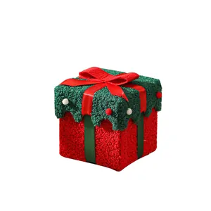 Hoogwaardige rode en groene pluchen kerstcadeaudoos met decoratieve strik en pompons.