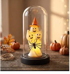 Warm glowing Halloween ghost lamp inside a clear glass dome on a rustic wooden table