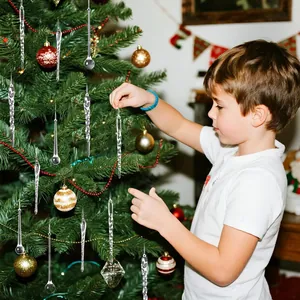 Un bambino decora con cura un albero di Natale con ornamenti trasparenti a forma di ghiacciolo