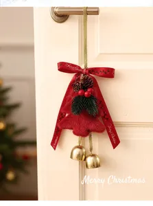 Close-up of a festive red plush Christmas tree ornament with golden bells and ribbon.