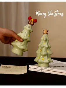 Detail of hand holding a glowing ceramic Christmas tree night light with star-shaped cutouts