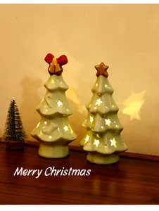 Detailed view of two glowing ceramic Christmas tree night lights on a wooden desk