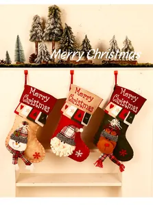 Set van drie feestelijke 3D pluche kerstkousen hangend aan een witte schouw decoratie