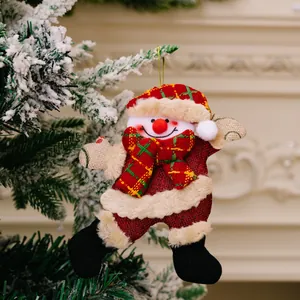 Close-up van een schattige pluchen kerstsneeuwpop hanger aan een besneeuwde tak