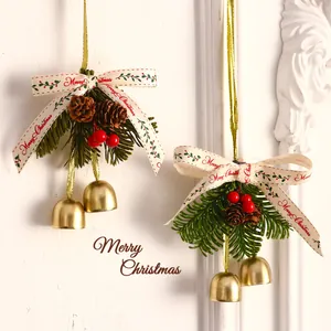 Festive Christmas hanging ornaments with golden bells, pine branches and cream bows on white wall