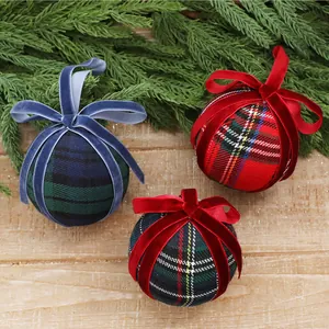 Detailed view of plaid Christmas ball ornaments with plush velvet bows on pine branches.