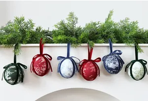Detailed view of 8cm fabric-wrapped Christmas baubles hanging with pine garland
