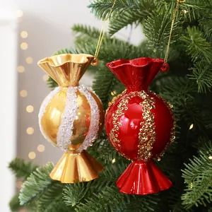 Detailansicht von glänzenden rot-goldenen Zuckerstangen-Anhängern an einem Weihnachtsbaum.