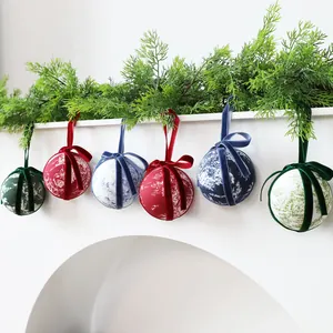 Set of patterned fabric-wrapped Christmas baubles hanging with green pine branches.