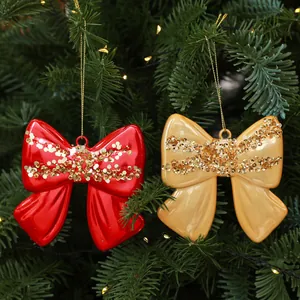 Primo piano di fiocchi glitterati rossi e oro su un rigoglioso albero di Natale.