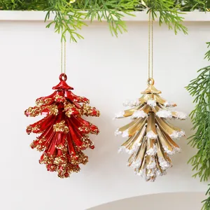 Rode en gouden dennenappel ornamenten met glitter hangend aan dennentakken.