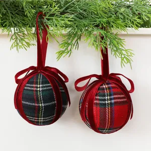 Close-up of plaid Christmas ball ornaments with red velvet bows and hanging loops.