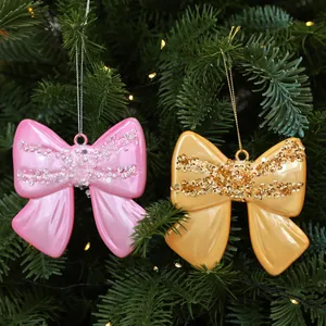 Primo piano di fiocchi lucidi rosa e oro con paillettes su un albero di Natale.