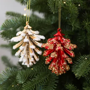 Detail van decoratieve dennenappel hangers in rood en goud aan een kerstboom