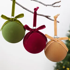 Close-up of velvet Christmas ornaments in green, red and tan with bows hanging on branch