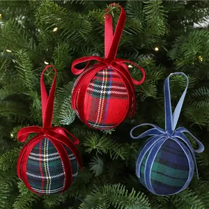 Detailed view of plaid Christmas ball ornaments with velvet ribbons on a tree.