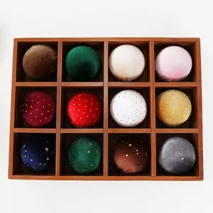 Detailed view of 12 multi-colored velvet Christmas balls in a wooden organizer box