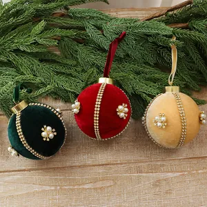 Nahaufnahme von luxuriösen Samt-Weihnachtskugeln mit Strassketten und Perlenakzenten.