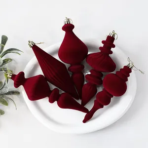 Detailopname van bordeauxrode geflokte kerstballen met fluweelzachte textuur op wit bord
