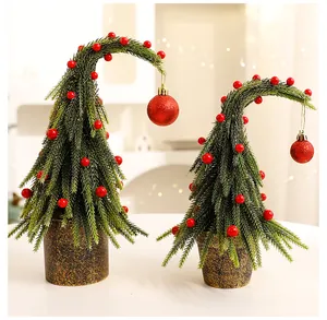 Set van twee grillige gebogen kerstbomen voor op tafel met rode bessen en ornamenten.