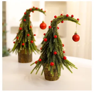 Detailopname van een mini-kerstboom met kromme hals, rode bessen en een glitterbal.