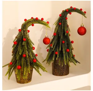 Speelse groene kerstboom met gebogen top, rode ballen en een decoratieve rustieke pot