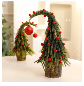 Detail van een kleine kerstboom met gebogen top en rode bessen versiering