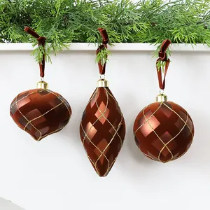 Dettaglio di palline di Natale floccate marroni con eleganti motivi a rombi glitterati oro.