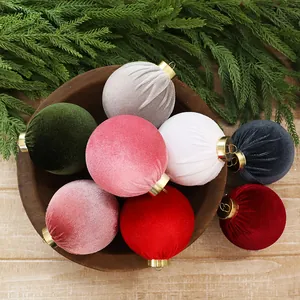 Multi-colored velvet Christmas ornaments set in a rustic wooden bowl with pine branches.