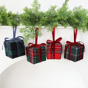 Set di quattro decorazioni scatole regalo scozzesi appese a una ghirlanda di pino verde.
