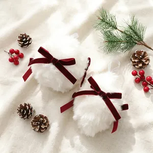 Détail de deux boules de Noël en fausse fourrure blanche avec nœuds en velours rouge