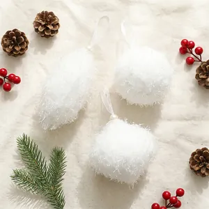 Gros plan d'ornements de Noël en peluche blanche avec pommes de pin et baies.