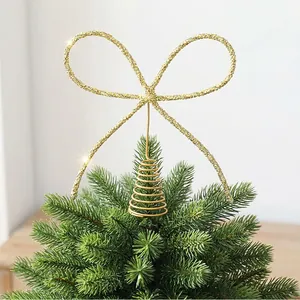 Détail d'une décoration de sommet de sapin en fer doré en forme de nœud scintillant.