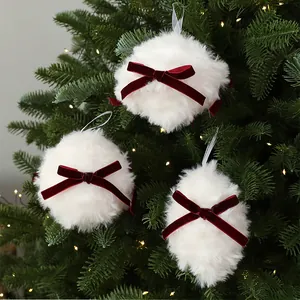 Détail rapproché de boules de Noël blanches en peluche avec nœuds en velours rouge