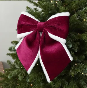 Detailopname van een bordeauxrode fluwelen kerststrik met witte bontrand in de boom