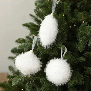 Vue détaillée de trois boules de Noël blanches en mousse suspendues à un sapin