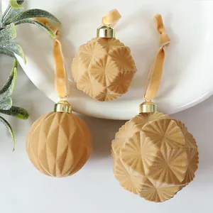 Close-up of elegant tan flocked Christmas ornaments with geometric textures on a white plate