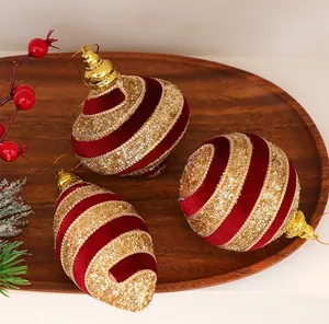 Detalle de adornos navideños de terciopelo rojo y purpurina dorada en bandeja de madera