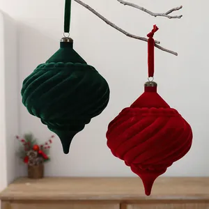 Detail of spiral flocked Christmas ornaments in red and green hanging on a branch