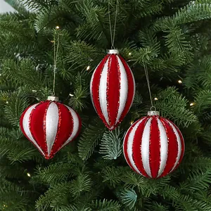 Detailed view of elegant red and white striped velvet Christmas ornaments on a tree.